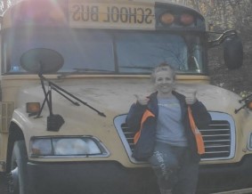 Woman smiling, standing in front of yellow school bus