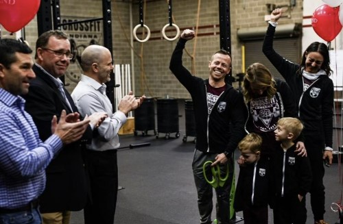 Crossfit gym in Indiana County PA opens with owner raising his arm in celebration as business members congratulate him and his family