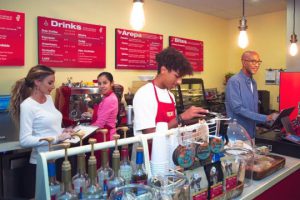 family working together behind the counter of a brightly colored cafe.